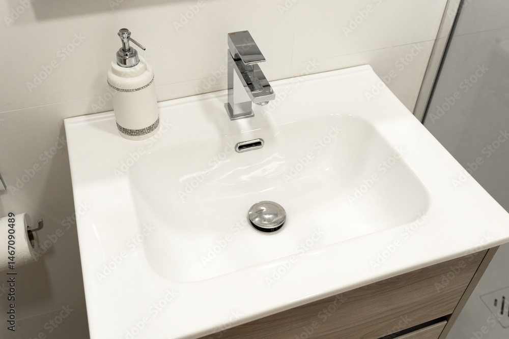Fototapeta premium Modern bathroom sink with a minimalist rectangular basin and sleek chrome faucet, complemented by a stylish soap dispenser. 