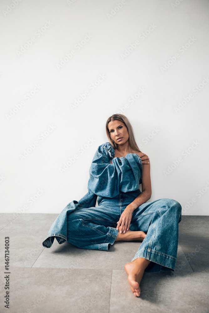Model posing gracefully in casual denim outfit against minimalistic background Model posing gracefully in casual denim outfit against minimalistic background