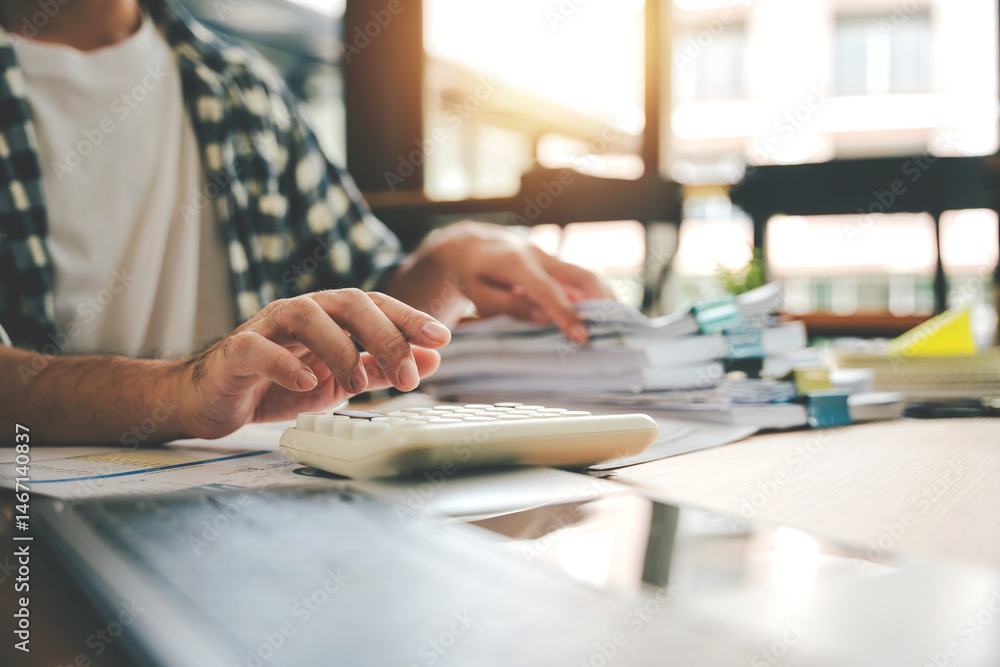 Accountant working at desk using calculator to calculate company's annual financial and tax report. financial concept Accountant working at desk using calculator to calculate company's annual financial and tax report. financial concept
