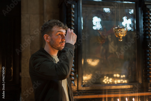 Quadro em tela Modern Orthodox Christian man praying and lighting candles in a monumental Georgian church