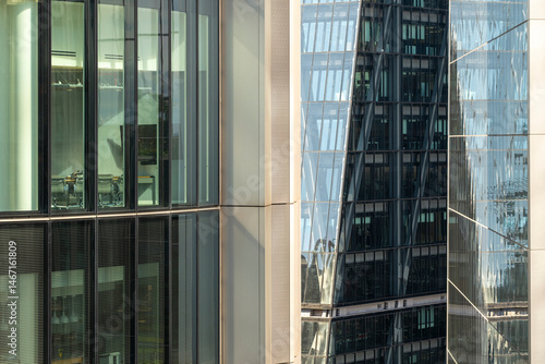 Close-up of illuminated glass offices with grid reflections and modern towers in background, ideal for corporate, finance and commercial urban visuals.
