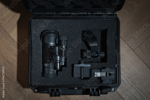 Professional night vision monocular with mounts, neatly packed in a protective shockproof case with a foam insert on a wooden background.