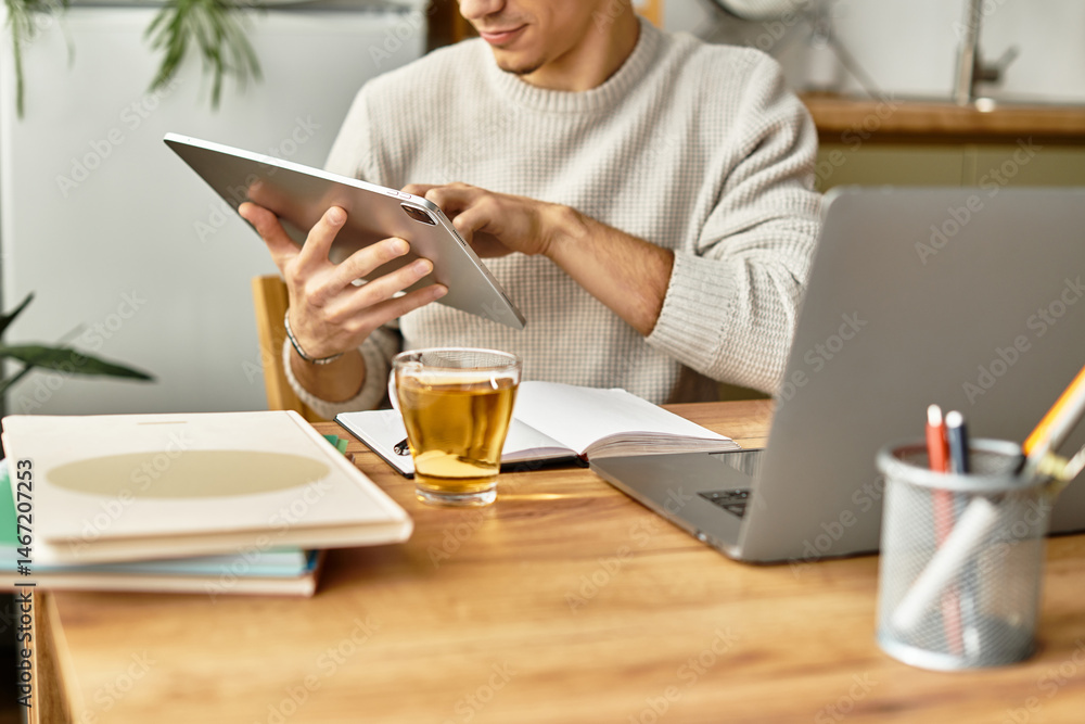Focused young man engaged in work while enjoying tea at a stylish home workspace Focused young man engaged in work while enjoying tea at a stylish home workspace