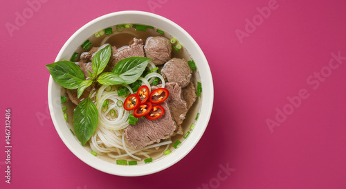 Close Up Top View Of A Bowl Of Vietnamese Pho Soup With Beef Meatballs And Garnishes On A Pink Surface