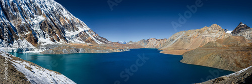 Tilicho lake with bright blue water in calm weather in autumn sunny day. Panoramic view. A sacred to Buddhists and Hindus lake in Himalaya mountain in Annapurna area, Nepal.