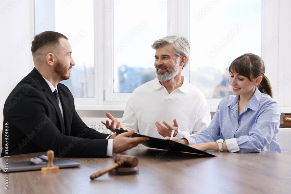 Clients signing notarial paperwork during meeting with lawyer at wooden desk indoors Clients signing notarial paperwork during meeting with lawyer at wooden desk indoors
