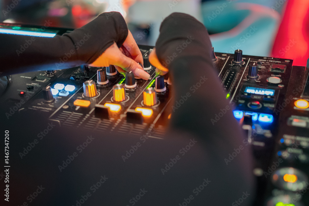A DJ's hands adjust knobs and sliders on a professional audio mixer, surrounded by illuminated buttons and controls, creating an engaging atmosphere for music mixing.