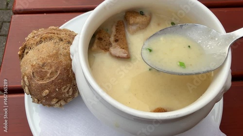 Asparagus soup in a small bowl Eating hot soup close up with brown bread, personal perspective