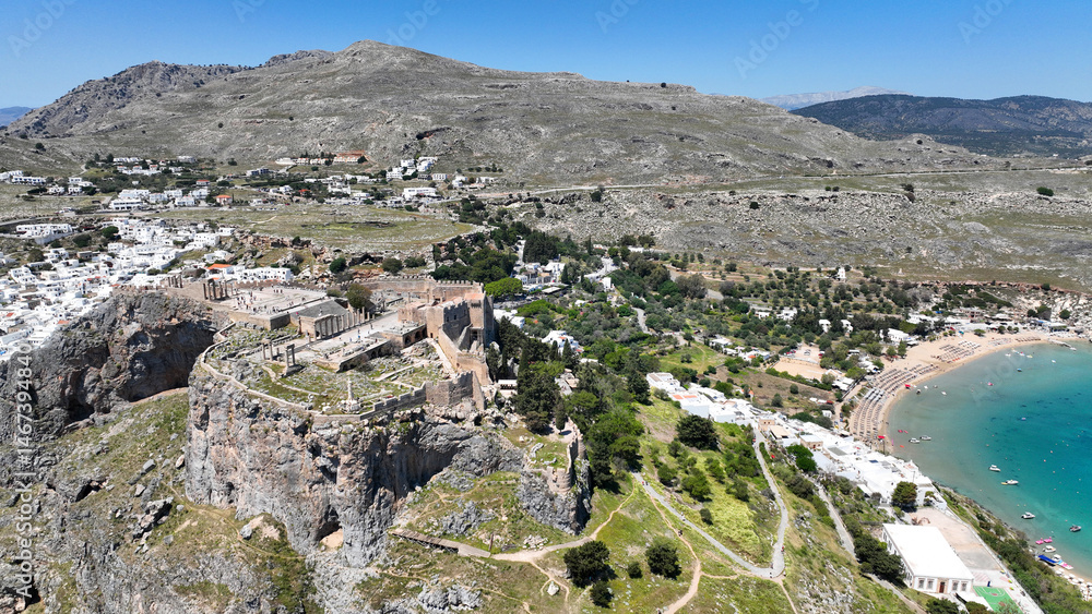 Aerial drone photo of stunning traditional village and medieval archaeological site of Acropolis of Lindos overlooking main beach and Saint Paul's bay, Rhodos island, Dodecanese, Greece