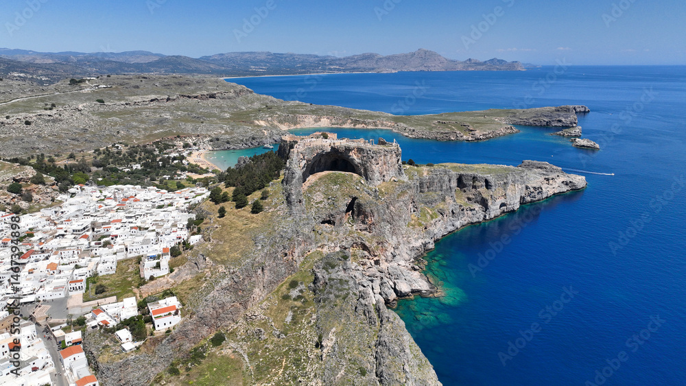Aerial drone photo of stunning traditional village and medieval archaeological site of Acropolis of Lindos overlooking main beach and Saint Paul's bay, Rhodos island, Dodecanese, Greece
