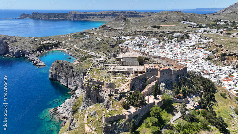 Aerial drone photo of stunning traditional village and medieval archaeological site of Acropolis of Lindos overlooking main beach and Saint Paul's bay, Rhodos island, Dodecanese, Greece