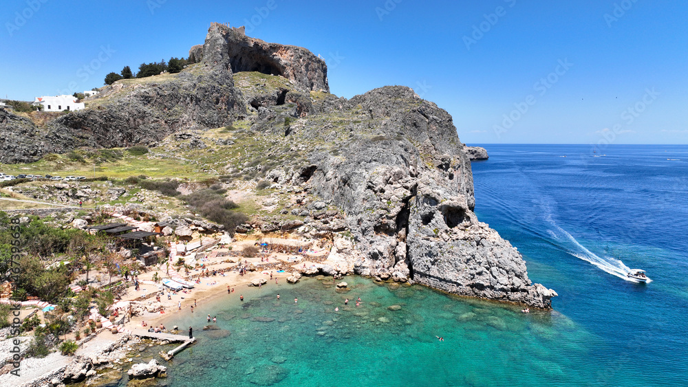Aerial drone photo of stunning traditional village and medieval archaeological site of Acropolis of Lindos overlooking main beach and Saint Paul's bay, Rhodos island, Dodecanese, Greece