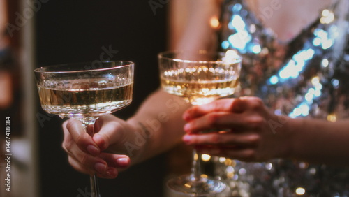 A beautiful girl holds glasses of champagne in her hands. Le coup cocktail glasses. Celebrates the New Year or a corporate holiday. Disco or retro style.
