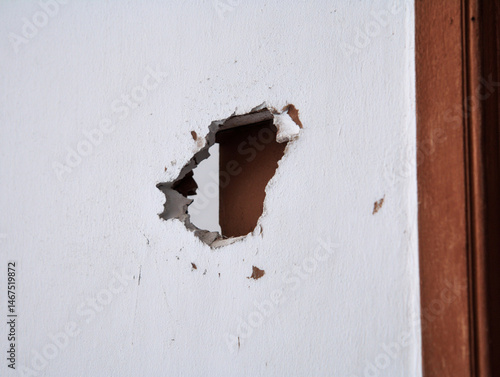 Cracked plaster wall with large irregular hole exposing interior space