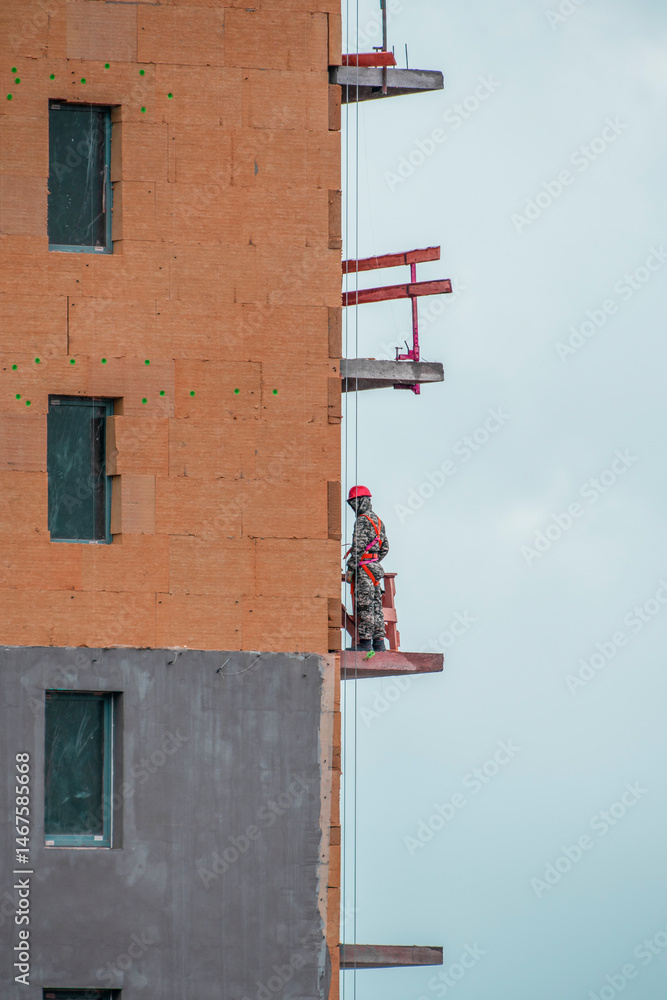 Obraz premium A construction worker on the wall of a building under construction on a spring day