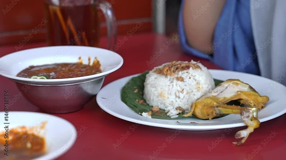 People enjoying a dish of uduk rice, fried chicken, and sliced cucumber. Suitable for food blogs, restaurant menus, stock videos and cooking websites People enjoying a dish of uduk rice, fried chicken, and sliced cucumber. Suitable for food blogs, restaurant menus, stock videos and cooking websites