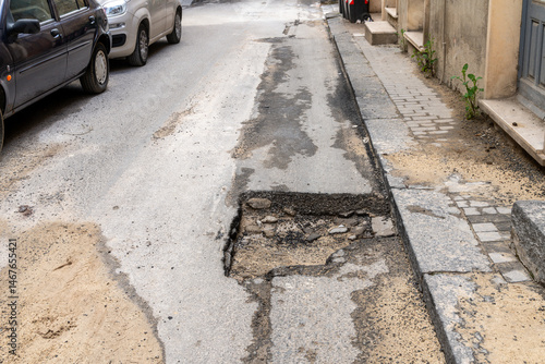 Damaged asphalt and exposed road surface with massive pothole
