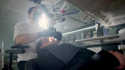 Male dentist working with dental microscope in stomatology clinic. Doctor using microscope for root canal treatment. 