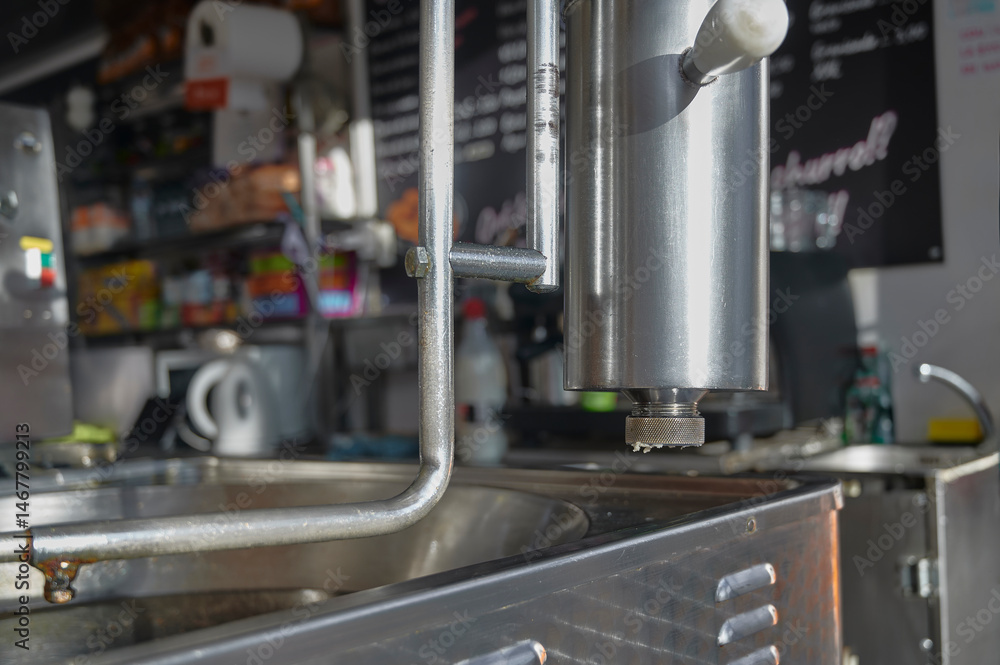 Fototapeta premium close-up view of a professional dough extruder dispensing churro batter over an industrial fryer in a churro shop. Rack and pinion machinery commonly used in the hospitality industry