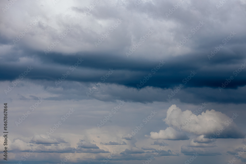Dark, dense storm clouds gather across the sky, with heavy rain visible in the distance and a few lighter clouds at the bottom ample copy space. Dark, dense storm clouds gather across the sky, with heavy rain visible in the distance and a few lighter clouds at the bottom ample copy space.