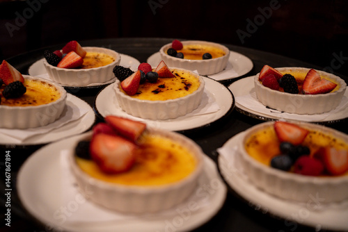 Fotografie Multiple crème brûlée desserts topped with fresh berries served on a tray