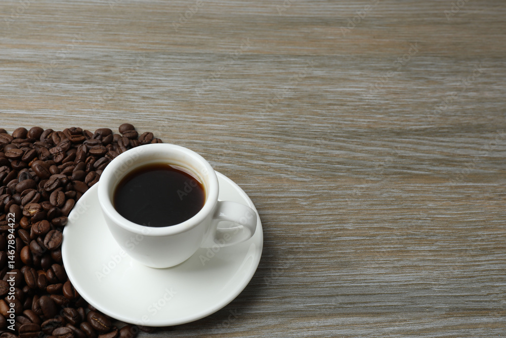 Obraz premium Hot coffee in a white coffee cup and many coffee beans scattered around