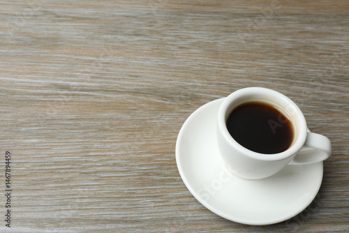 Hot coffee in a white coffee cup and many coffee beans scattered around 