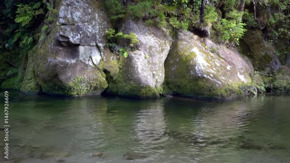 Three large boulders on opposite shore of calm river Three large boulders on opposite shore of calm river