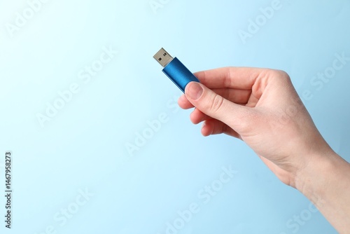 Fényképezés Woman holding USB flash drive on light blue background, closeup
