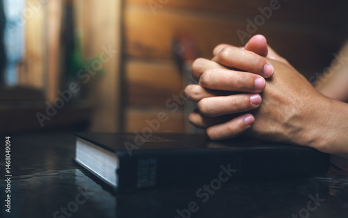 Obraz na plátne Close up of a man praying, hands clasped together on Bible, devotional concept