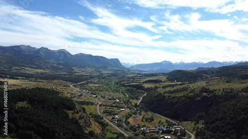 El río Coyhaique fluye entre árboles frondosos y paisajes andinos en un vuelo de dron cinematográfico.

