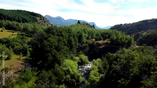 Vista aérea del río Coyhaique rodeado de árboles y montañas verdes en la inmensidad patagónica.