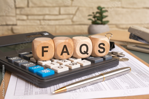 Wooden cubes with FAQS letters on calculator and spreadsheet background