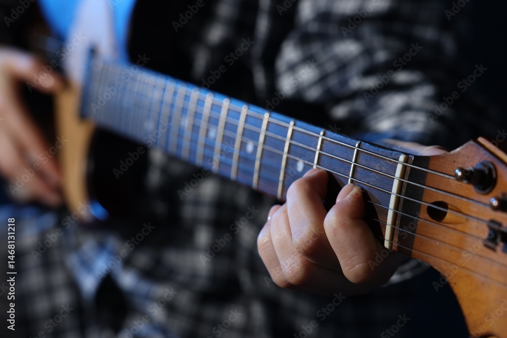 Obraz premium Woman playing guitar on dark background, closeup