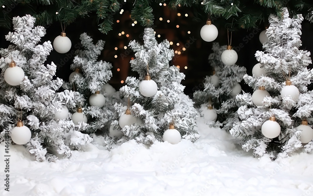 Multiple green Christmas trees decorated with white ornaments, set indoors with soft lighting.