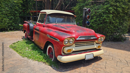 Red vintage truck parked on road beside traffic light with tree and house or home background. Retro or classic vehicle and old car style for show.