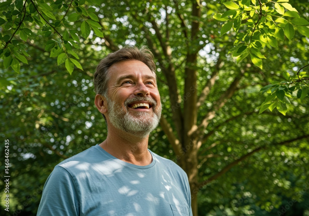 A smiling man gazes upwards at the leaves of a tree, bathed in sunlight. A smiling man gazes upwards at the leaves of a tree, bathed in sunlight.