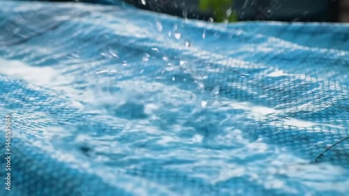 Rain Drops Falling on Blue Protective Tarp Creating Ripples and Splashes