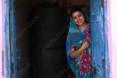 Obraz na płótnie Portrait of Indian poor rural woman from village in colorful traditional saree standing outside their home
