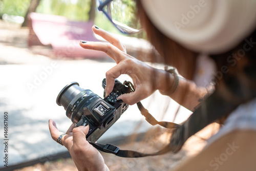 Female photographer adjusting settings on her camera, preparing for a shoot in a skatepark environment