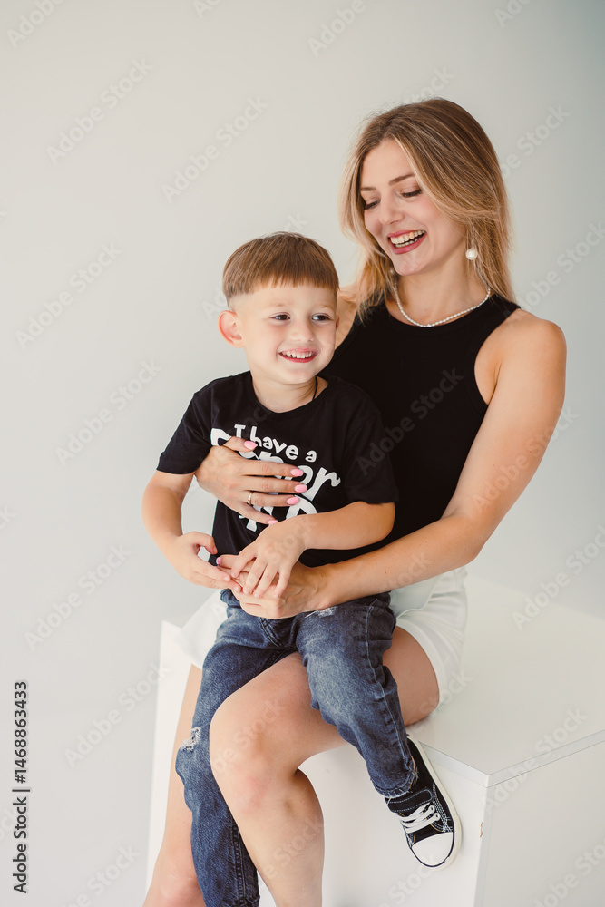 Mom and 4 year old son smiling and hugging on a white background. Warm relationship between mom and son. Concept of family relationships between mom and son.