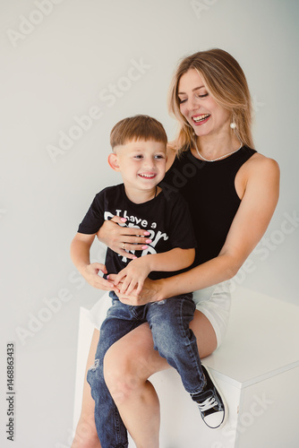 Obraz na płótnie Mom and 4 year old son smiling and hugging on a white background. Warm relationship between mom and son. Concept of family relationships between mom and son. w salonie