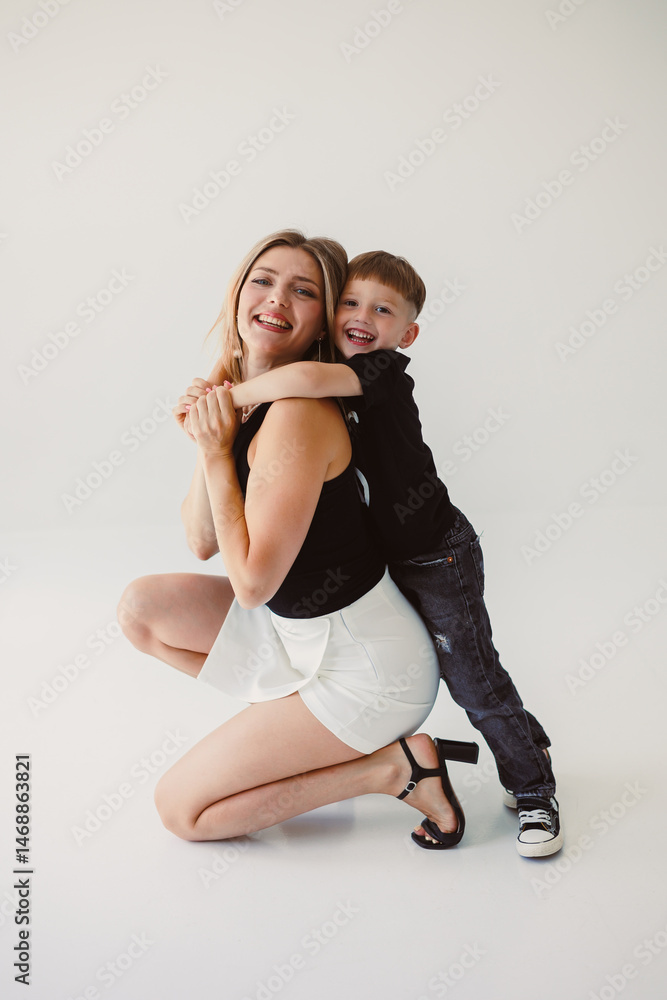 Mom and 4 year old son smiling and hugging on a white background. Warm relationship between mom and son. Concept of family relationships between mom and son.