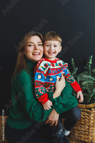 Obraz na płótnie Mother and little son at home on Christmas, child smiles at mother, congratulates and gives unexpected gift. Woman mother receives gift from son on birthday. Family holiday, love concept w salonie