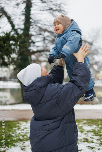 Obraz na płótnie Smiling mother playing with her one-year-old son on the street. Child development and active recreation. Toddler boy playing with his mother on the playground. w salonie