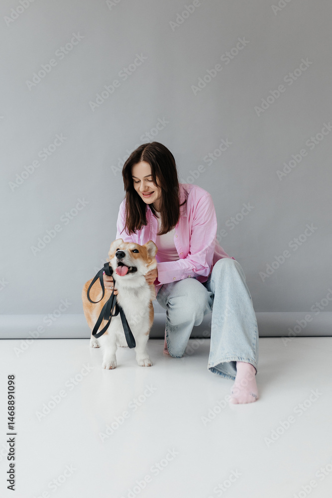 Cute brunette woman in white t-shirt and jeans hugging corgi puppy on white background. Love for animals, pets concept. cheerful woman holding welsh corgi dog.