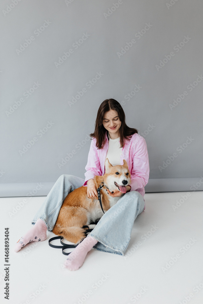 Cute brunette woman in white t-shirt and jeans hugging corgi puppy on white background. Love for animals, pets concept. cheerful woman holding welsh corgi dog.