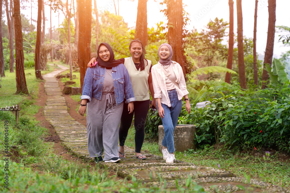 Fototapeta premium Three Young Asian Women Walking Together and Smiling in Forest Path