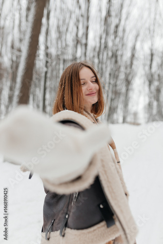 Obraz na płótnie Pretty woman in a fur coat with a big warm scarf around her neck on a winter walk. Woman smiles and rejoices in the snow in winter. Girl walks through a snowy park in winter. w salonie