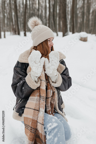 Obraz na płótnie Pretty woman in a fur coat with a big warm scarf around her neck on a winter walk. Woman smiles and rejoices in the snow in winter. Girl walks through a snowy park in winter. w salonie